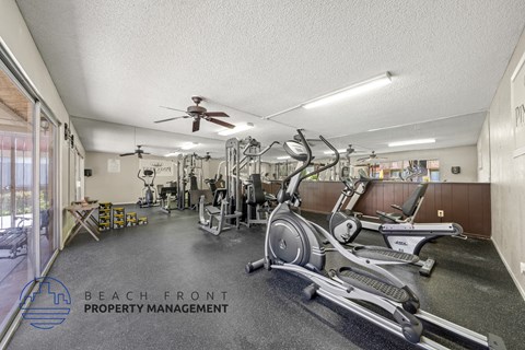 A gym with a variety of equipment including treadmills, stationary bikes, and weight machines.