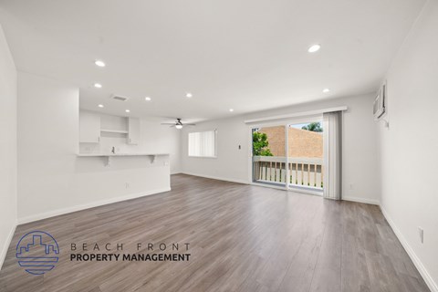 A spacious room with wooden flooring and a ceiling fan, managed by Beach Front Property Management.