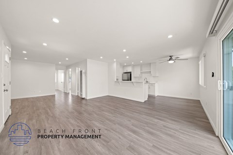 A spacious room with wooden flooring and a ceiling fan.