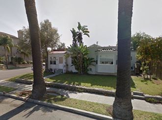 a house on a street with palm trees