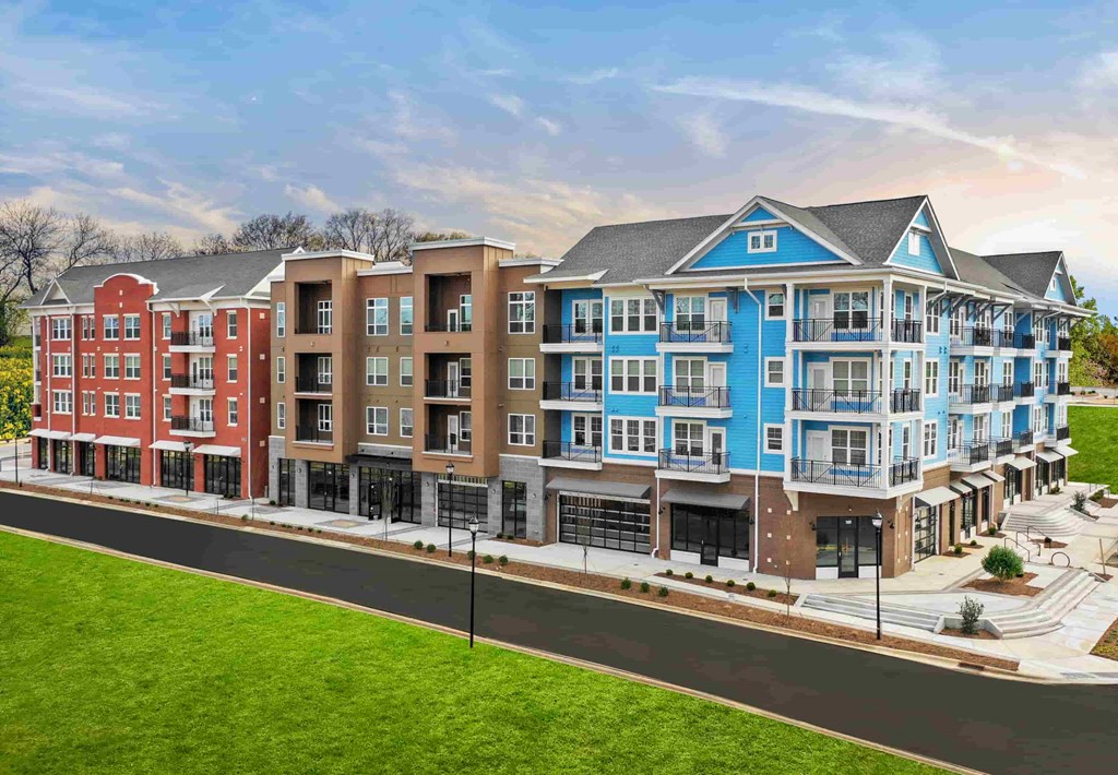 A row of modern apartment buildings with red, brown, and blue facades.