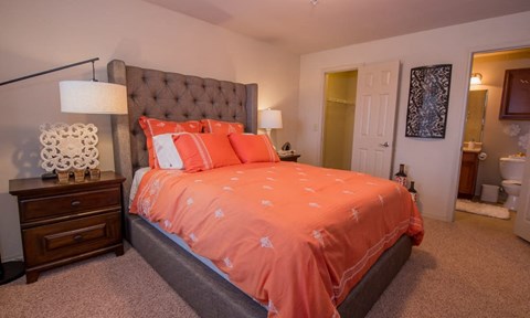 A bedroom with a bed covered in orange bedding.