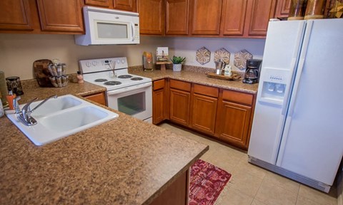 A kitchen with a white fridge, white microwave, white stove and white sink.
