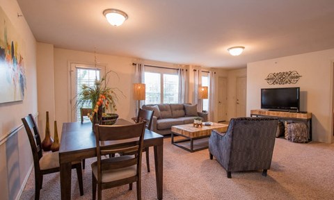 A living room with a couch, chairs, and a television.