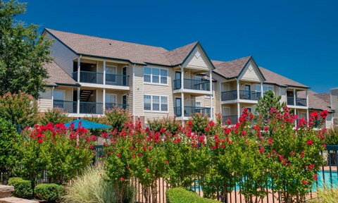 A building with a pool and red flowers in front.