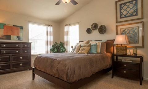 A bedroom with a bed, nightstand, and a ceiling fan.