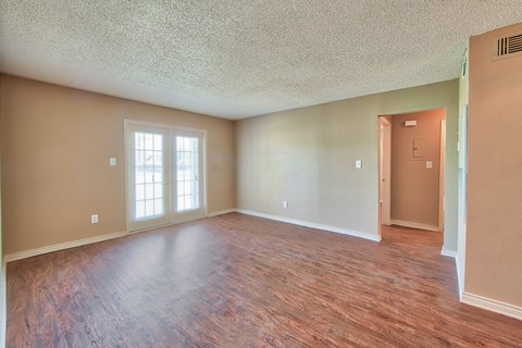an empty living room with a hard wood floor and a door