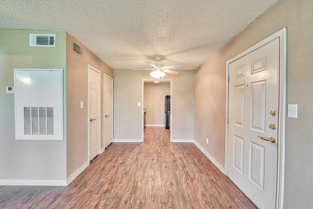 an empty hallway with a ceiling fan and white doors