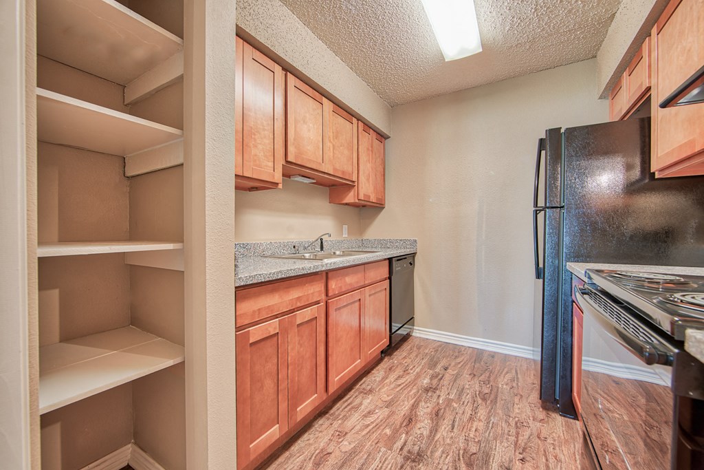 an empty kitchen with wooden cabinets and a black refrigerator