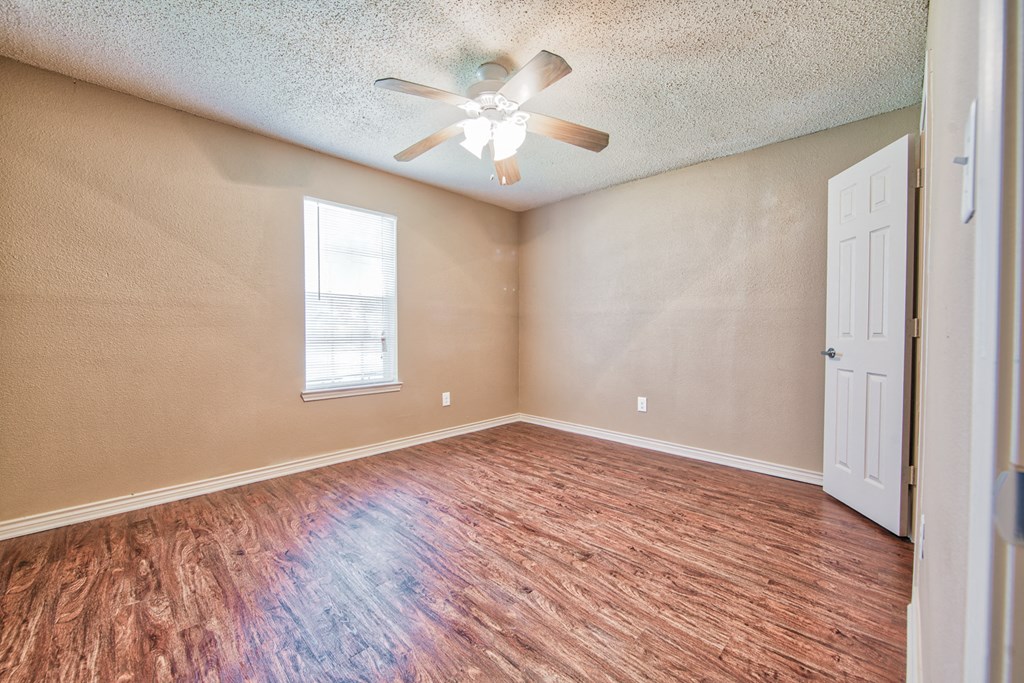 an empty living room with a ceiling fan and a window