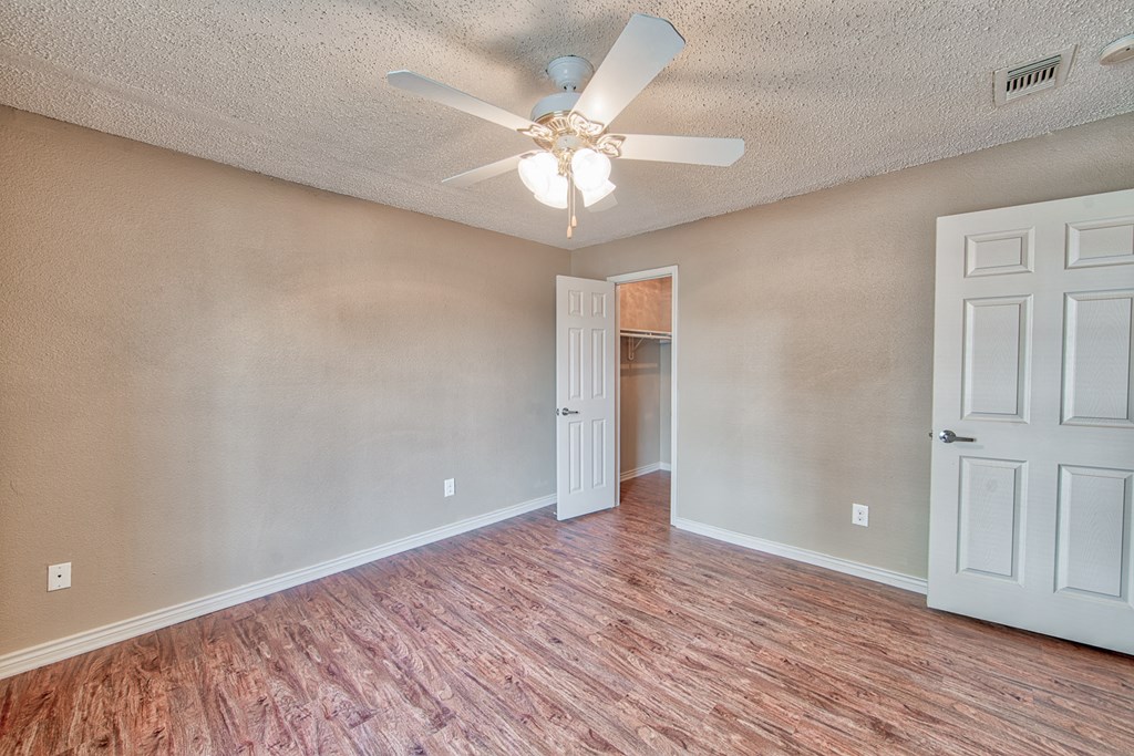 an empty living room with a ceiling fan and a door to a closet
