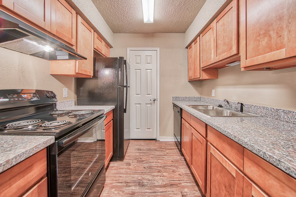 a kitchen with wood cabinets and granite counter tops and a black refrigerator