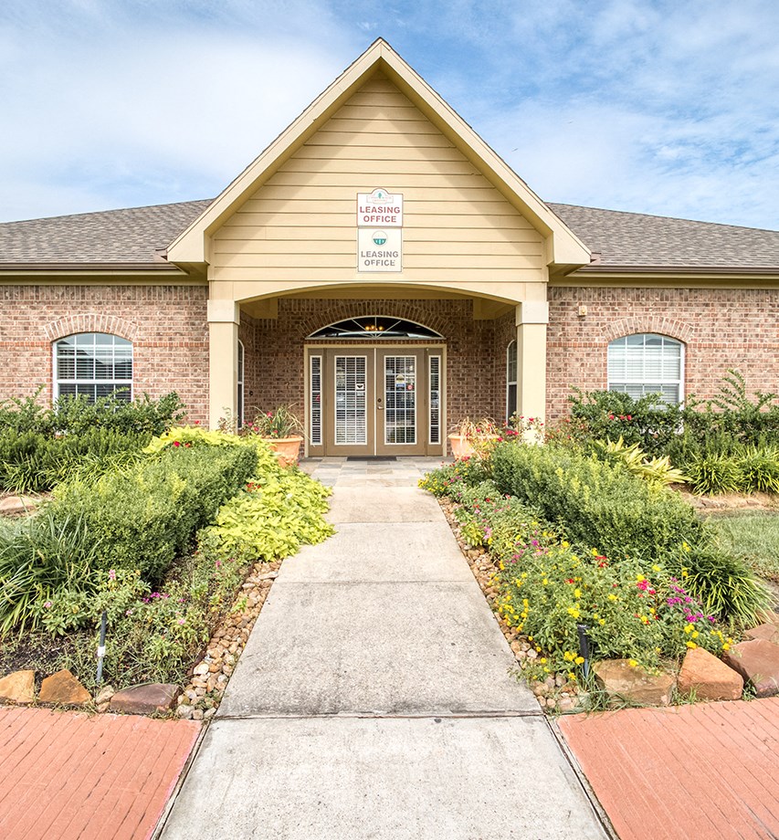 the front of a house with a walkway and plants in front