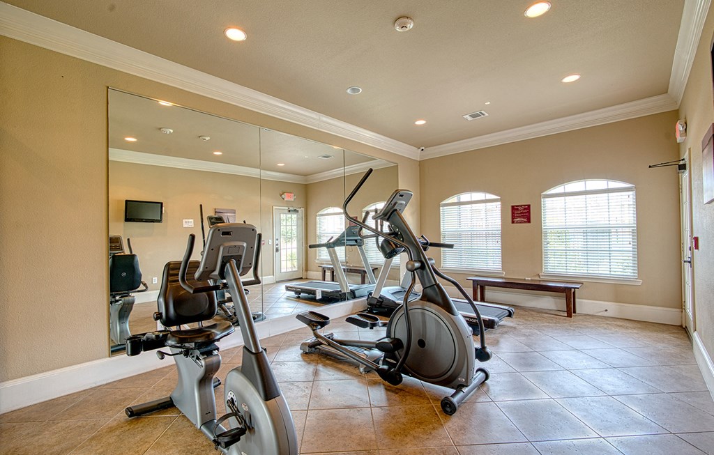 the gym has a lot of exercise equipment and mirrors