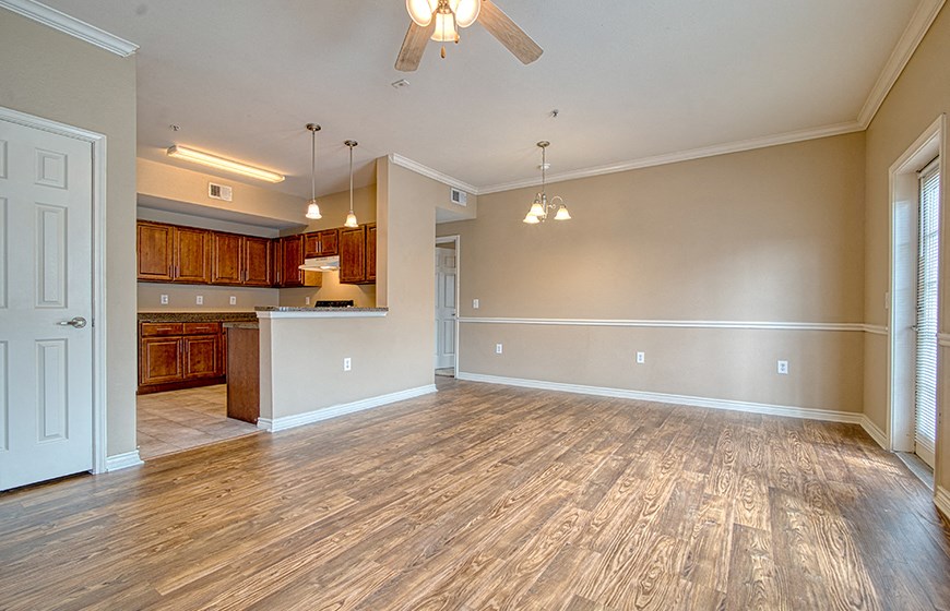 an empty living room and kitchen with wood flooring