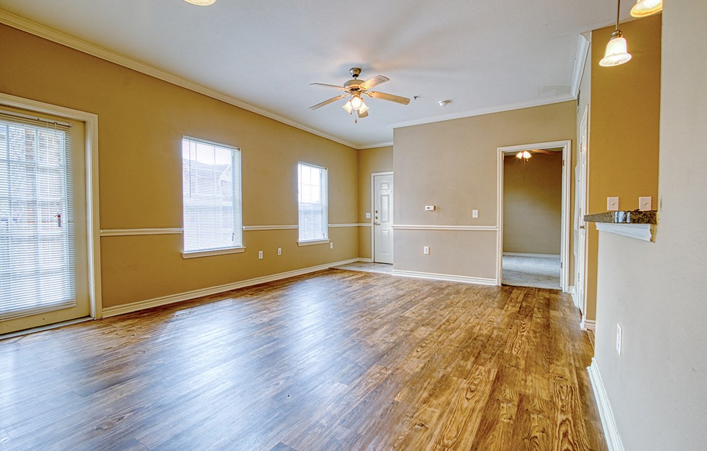 an empty living room with wood floors and a ceiling fan