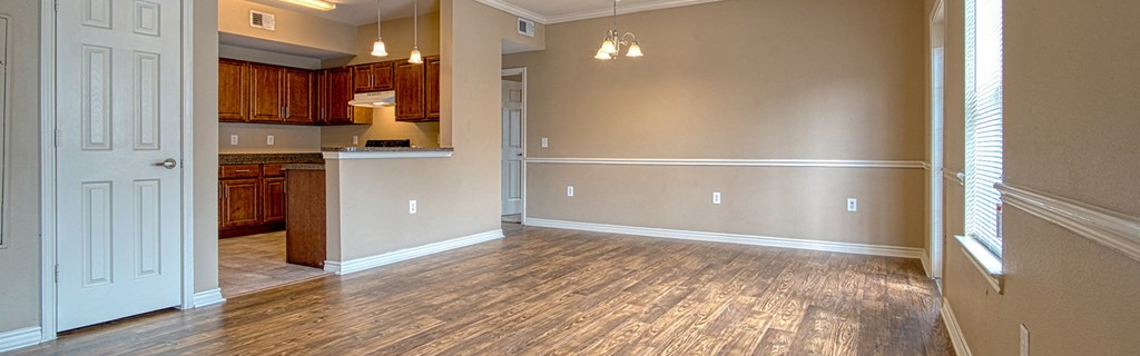 an empty living room and kitchen with wood flooring