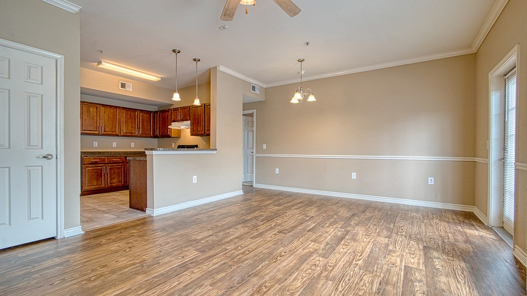 an empty living room with wood floors and a kitchen