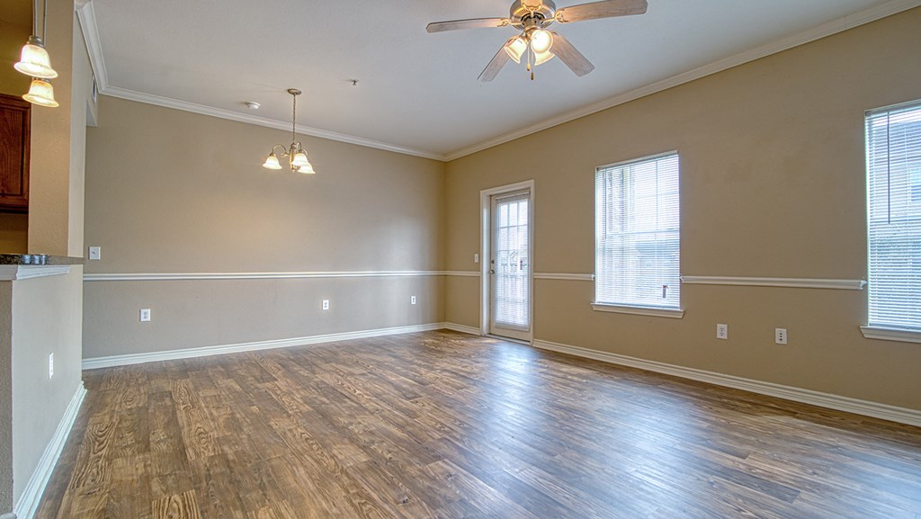 an empty living room with wood floors and a ceiling fan