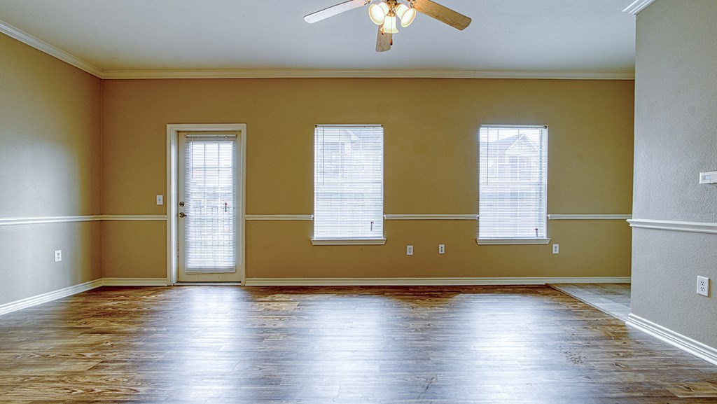 an empty living room with yellow walls and a ceiling fan
