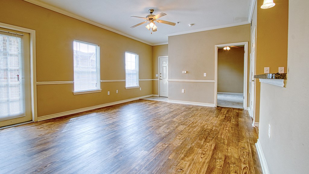 an empty living room with wood floors and a ceiling fan