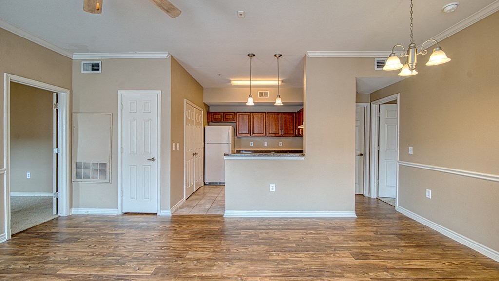 an empty living room and kitchen with a wood floor