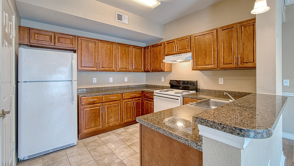 an empty kitchen with wooden cabinets and a white refrigerator