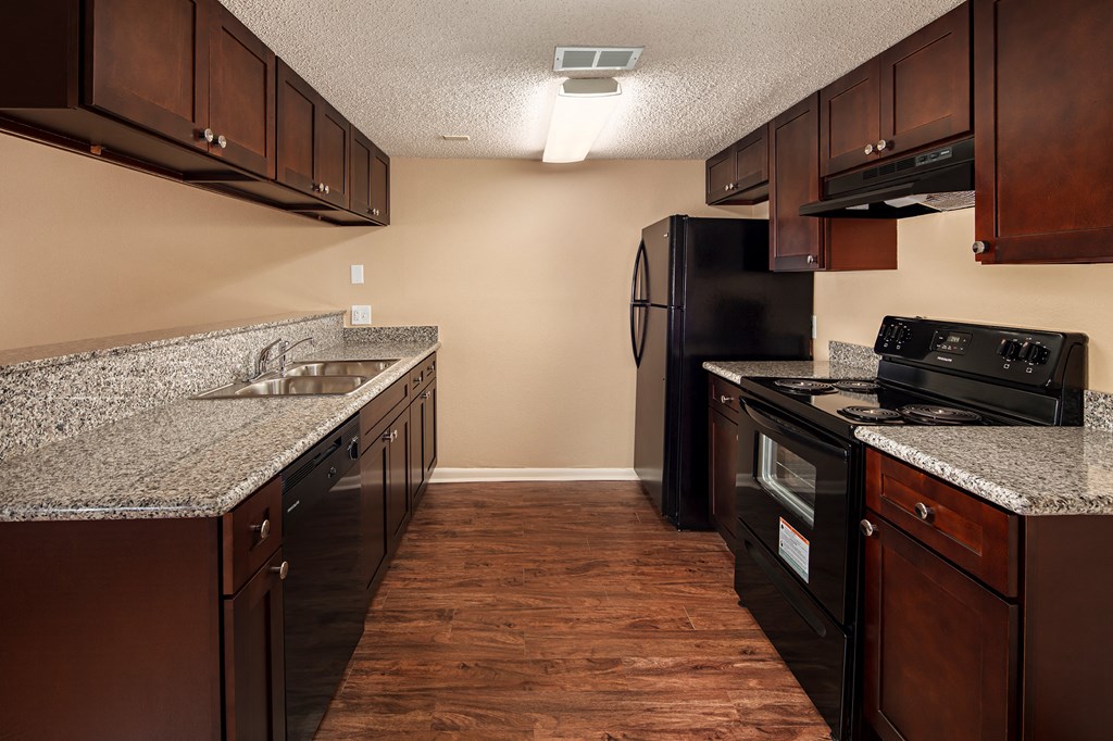 a kitchen with granite countertops and dark wood cabinets