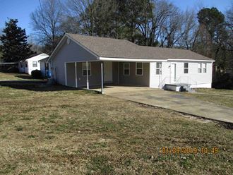 the front of the house has a large yard and a patio