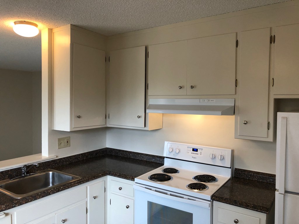 an empty kitchen with white appliances and white cabinets