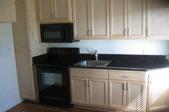 A kitchen with black countertops and wooden cabinets.