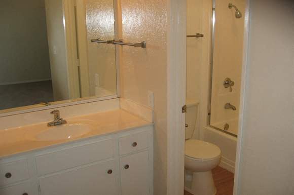 A white bathroom with a toilet, sink, and mirror.