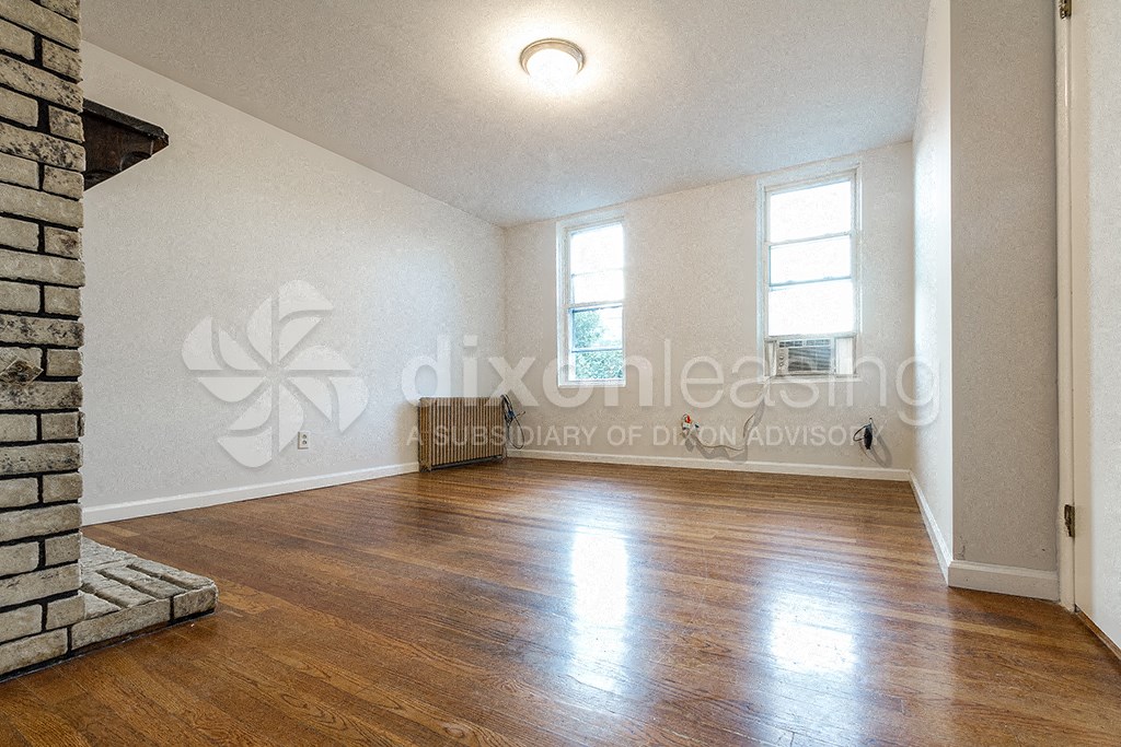 a large empty living room with wood floors and a fireplace