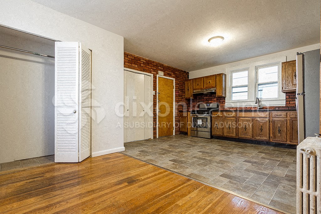 a small kitchen with a refrigerator and wooden floors