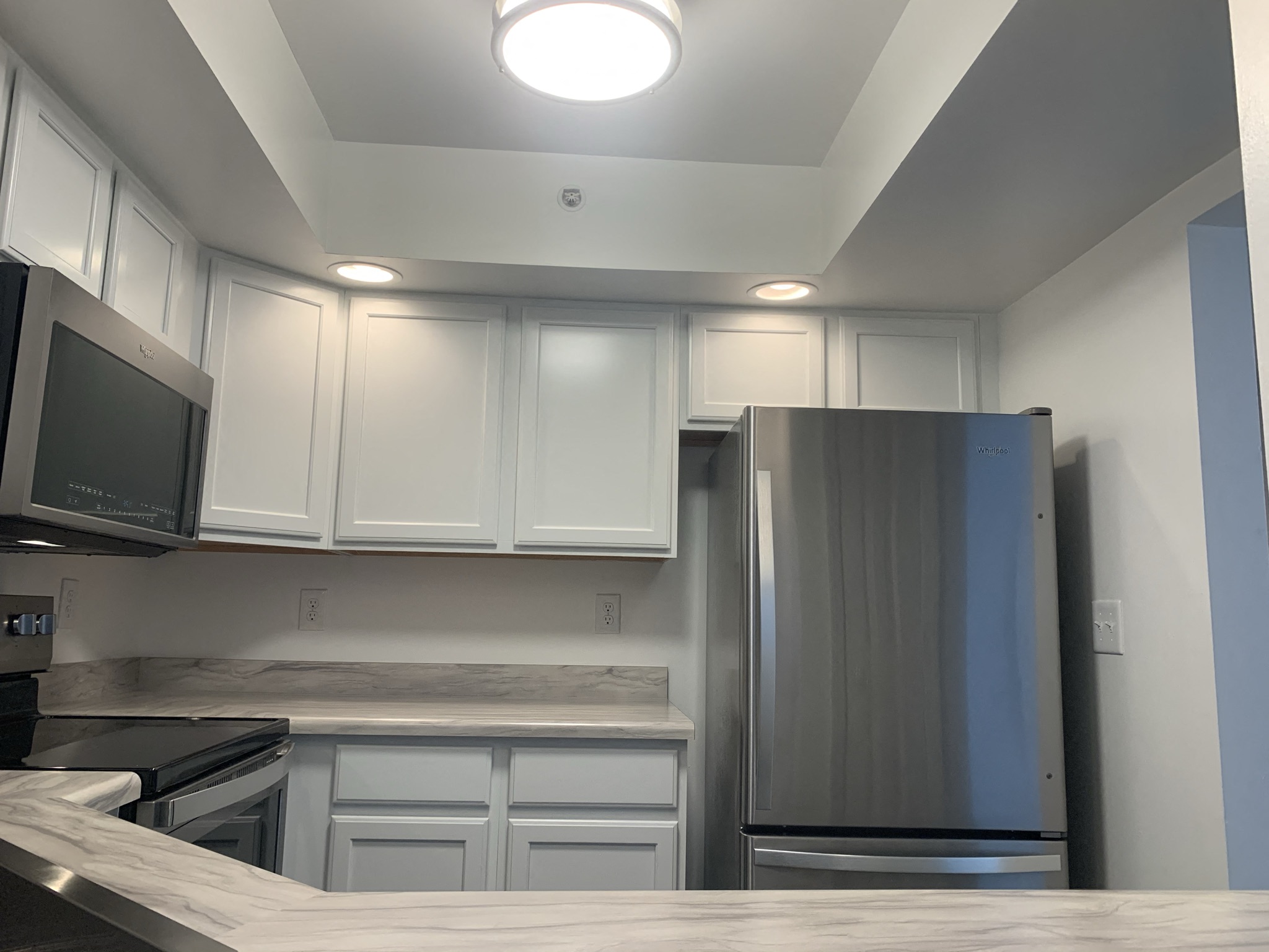 a kitchen with white cabinets and a stainless steel refrigerator