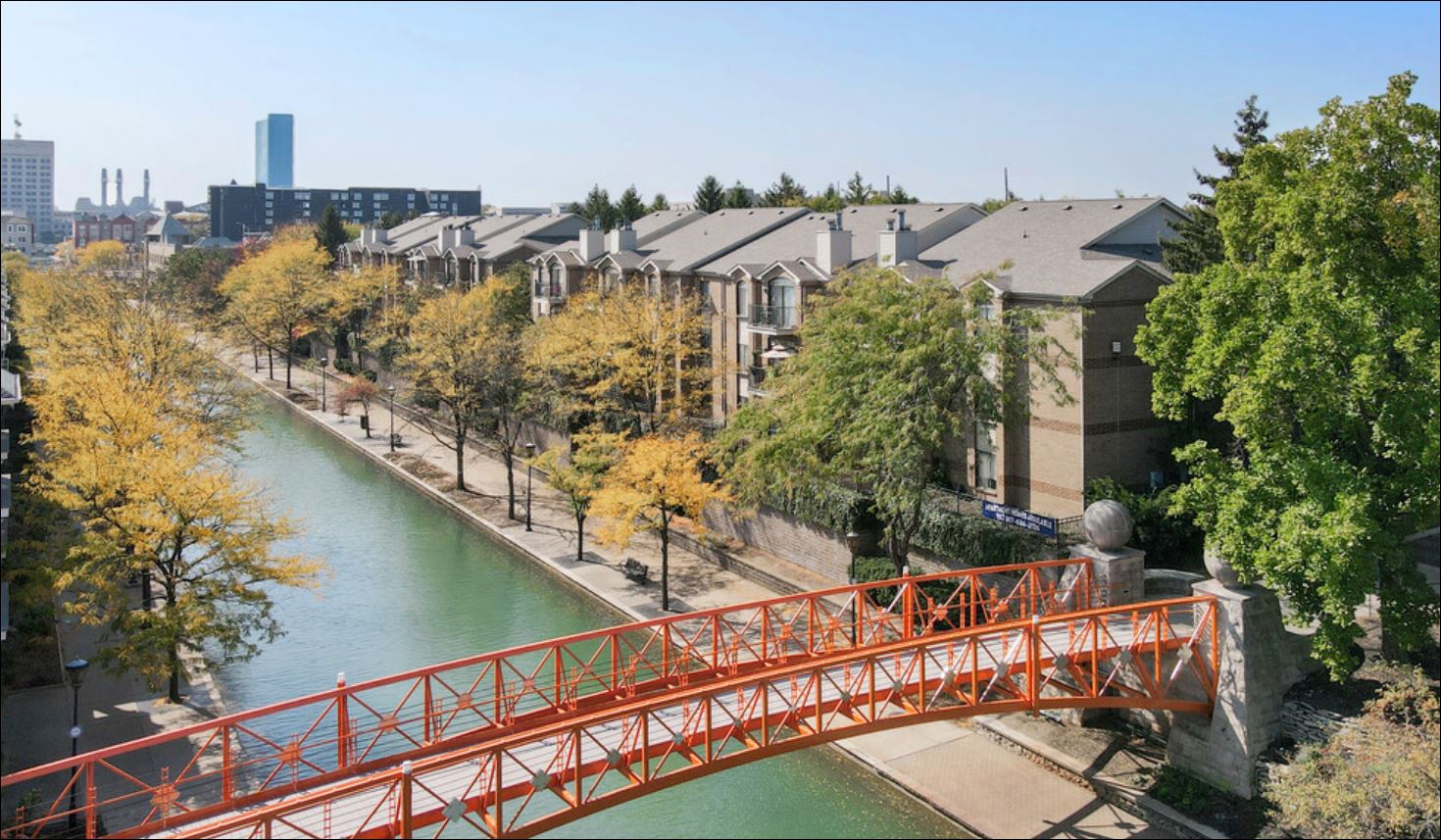 a red bridge over a river with a city in the background