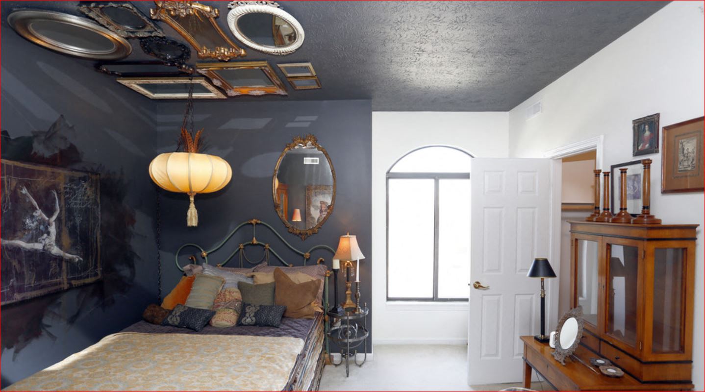 a bedroom with a bed and a black wall and a ceiling with a mirror