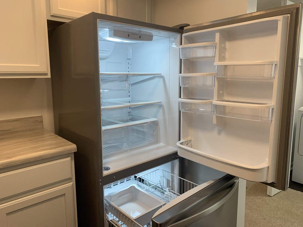 an empty refrigerator with its door open in a kitchen