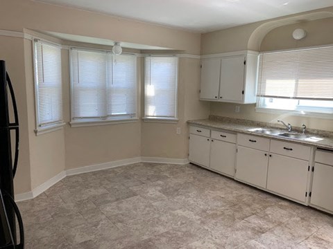 A kitchen with white cabinets and a tiled floor.