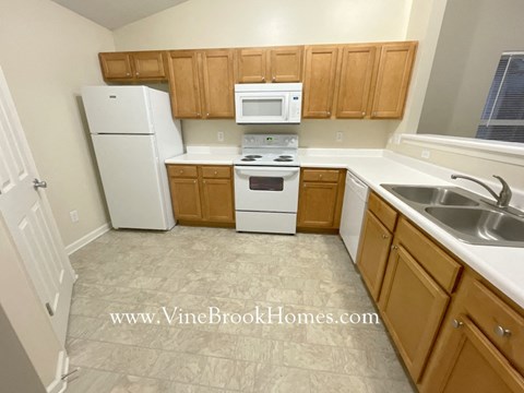 A kitchen with wooden cabinets and white appliances.