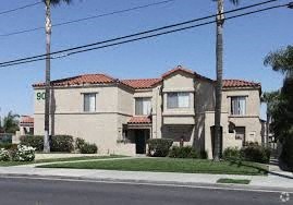 A house with a red tile roof and a palm tree in front.
