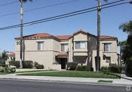 A house with a red tile roof and a palm tree in front.