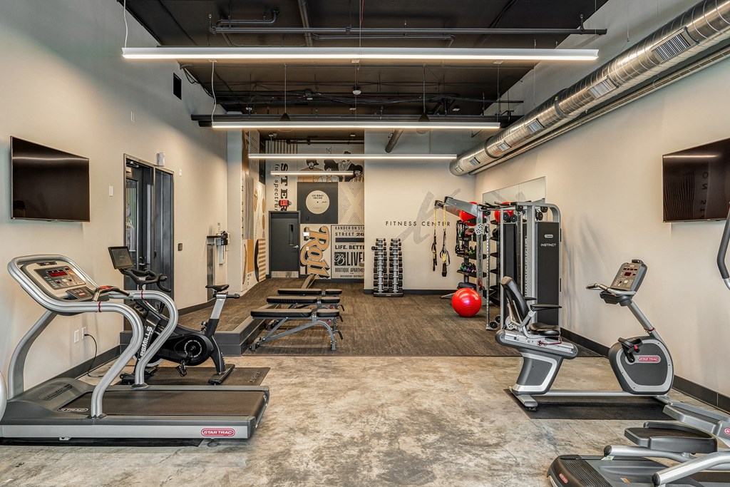 a gym with treadmills and other exercise equipment in a room with a tv