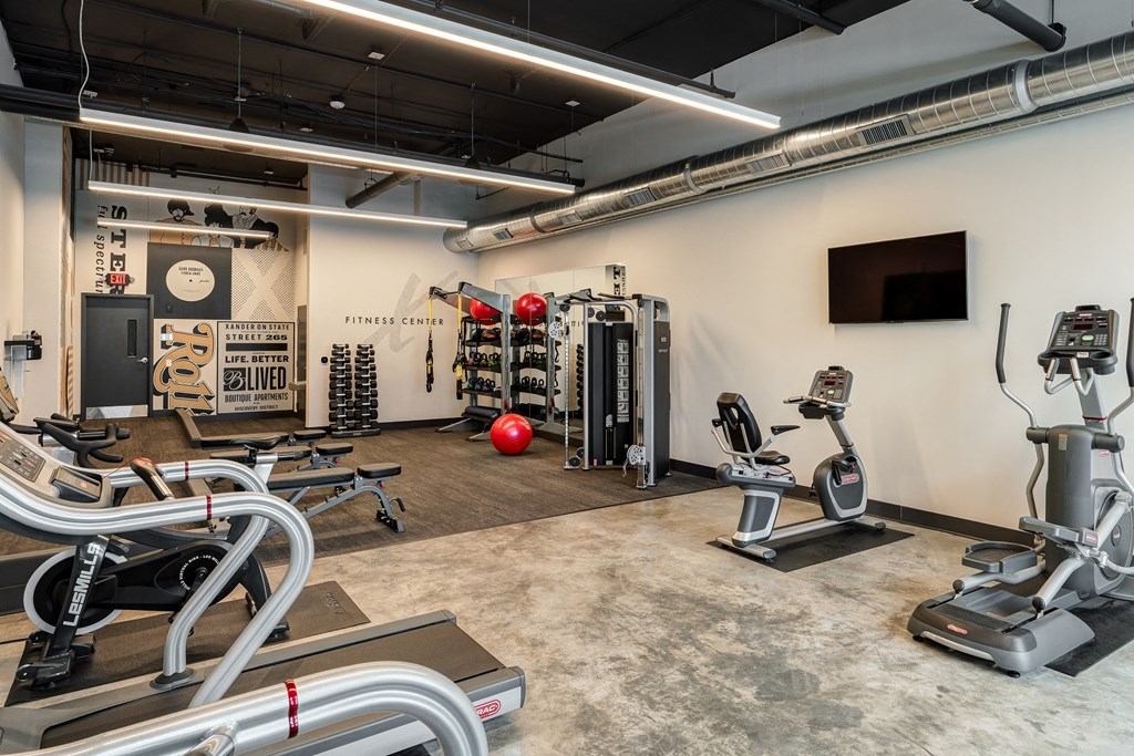 a gym with treadmills and other exercise equipment and a tv on the wall