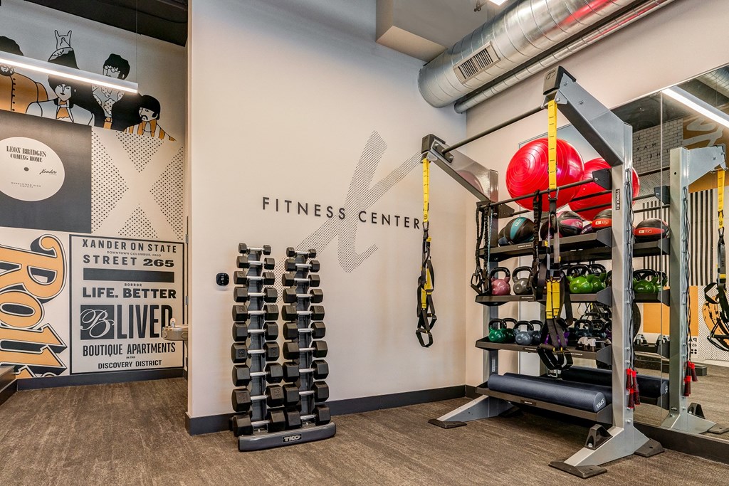 a fitness center with weights and a wall with the gym logo