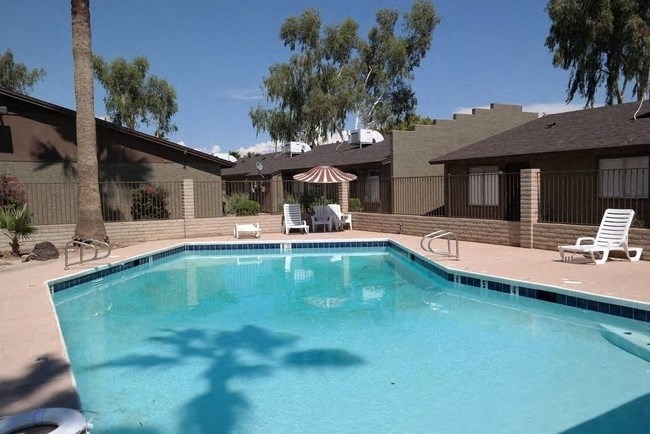 a pool with two chairs and a umbrella in front of a house