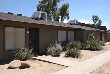 a brown house with a roof and some plants