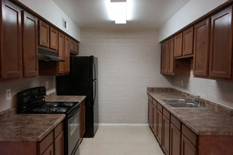 an empty kitchen with wooden cabinets and a black refrigerator