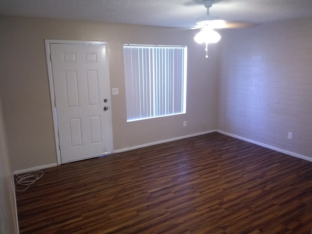 an empty living room with wood floors and a white door
