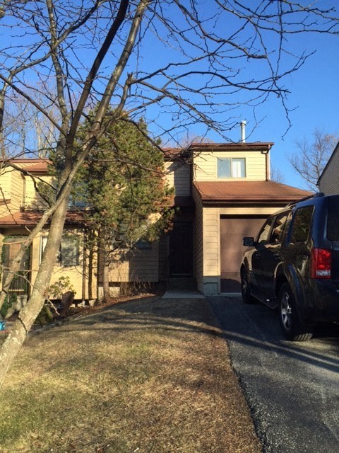 A black truck is parked on a driveway in front of a house.